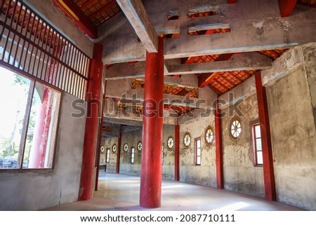An old and beautiful abandoned Chinese temple hallway There was a red column against the surface of the decaying cement wall.