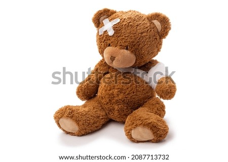 medicine, healthcare and childhood concept - teddy bear toy with bandaged paw and patch on head on white background