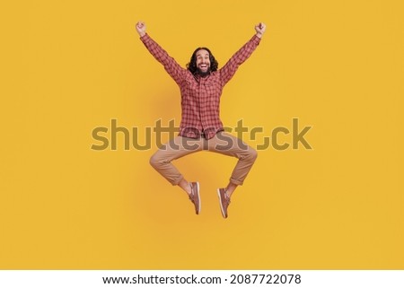 Photo of astonished crazy man jump celebrate victory wear checkered shirt isolated on yellow color background