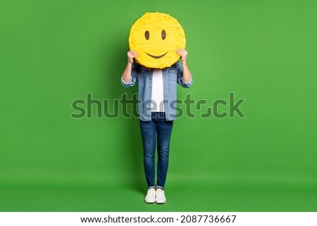 Full length body size photo of man keeping smile icon hiding face isolated bright green color background