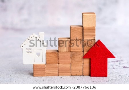 Model of wooden houses and wooden cubes with price word and red up arrow .Increase property value concept