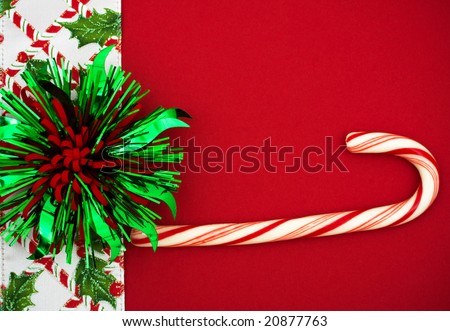 Green and Red bow and candy cane with holly berries and leaf border on red background, Christmas border
