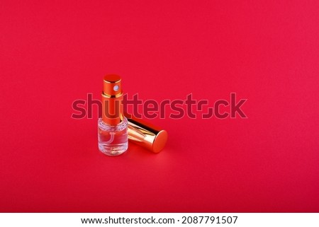 bottle with liquid with a golden cap that lies next to it on a red background. High quality photo