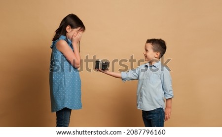 Little kids friendship and love. Little boy giving a little girl a gift. Present for a birthday, valentine's day or other holiday, ready for your text, logo or symbols. Isolated on white background