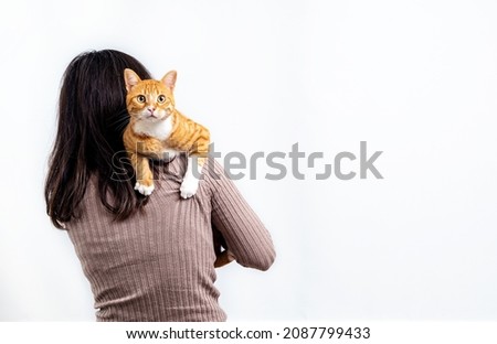 Close up photo of young adult woman smiling with domestic tabby cat on isolated background. Cat and pet lover concept.