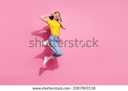 Photo of dreamy adorable woman wear yellow outfit jumping high listening music headphones empty space isolated pink color background