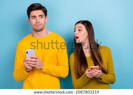 Photo of curious lady look screen husbands phone dont want show his post social media isolated over blue color background