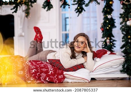 A beautiful girl lies in bed on the floor in anticipation of the new year. Around the New Year's decor. New Year's holidays. Family traditions 