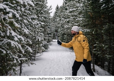 The use of technology. A male videographer shoots the winter nature of the forest with a camera.