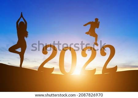 Happy New Year Numbers 2022, Silhouette a man handsome jumping feels happy moving  and woman practicing yoga early morning sunrise over the horizon background, Health and Happy new year concept.