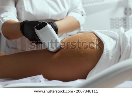 Young African woman getting laser hair removal on her thighs.