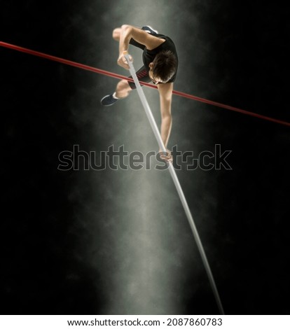Professional pole vaulter training at the stadium at night. Soft focus effect. Copy space background