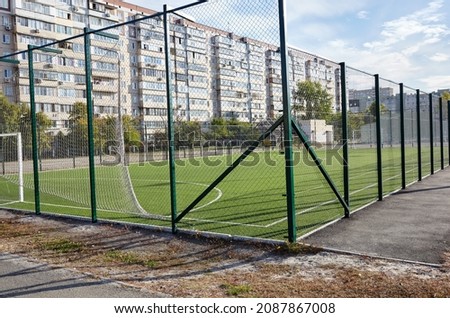 Lawn field for playing football behind the green fence mesh. Close-up of soccer field with green grass
