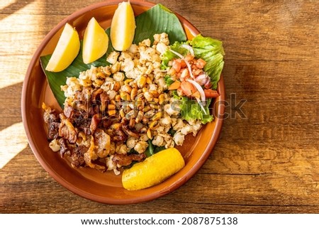 Overhead view of mote con chicharrón, corn with pork skin in an earthenware bowl with potatoes and toast. Traditional dish from the sierra of Andean countries Royalty-Free Stock Photo #2087875138