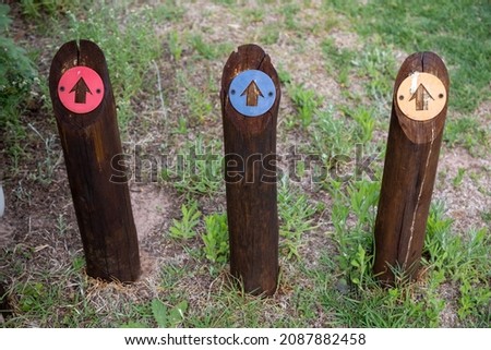 Three wooden poles with arrows pointing forward.  The arrows are red blue and yellow