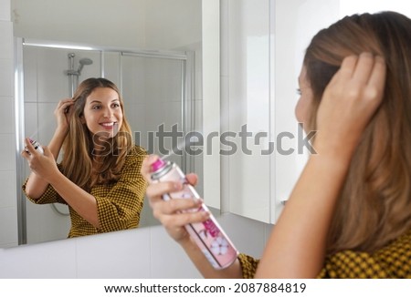 Attractive young woman applying dry shampoo on her hair. Fast and easy way to keep hair clean with dry shampoo. Royalty-Free Stock Photo #2087884819