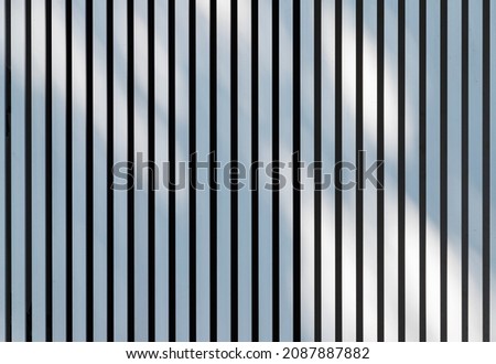Soft shadows pattern is over white metal fence. Background photo texture