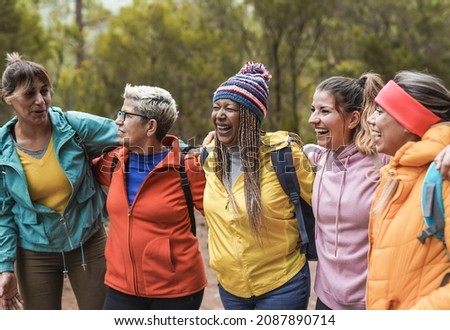 Multiracial women enjoy trekking day in nature while hugging each other