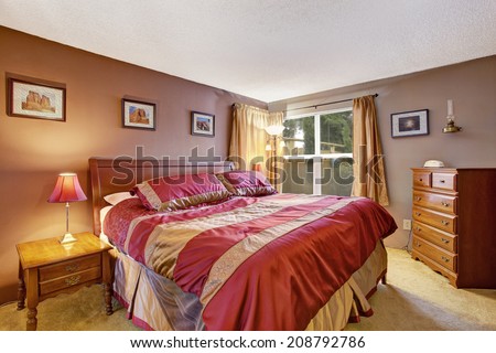 Bedroom interior with beautiful bed in red and mocha, dresser and nightstand