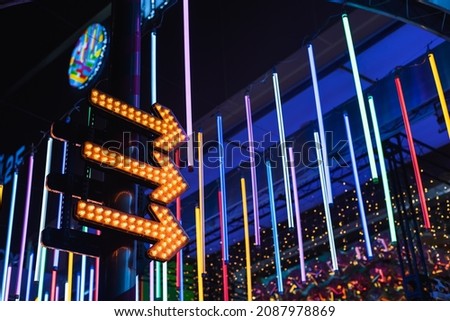 Colorful neon lights with arrow signs at night low angle view background