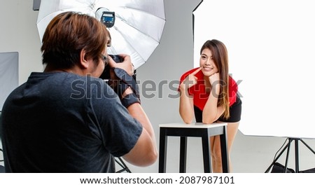 Photographer and cout young teen Asian model working in modern lighting studio with many kinds of flash and accessories. Stock shooting for commercial photo and contents concept.