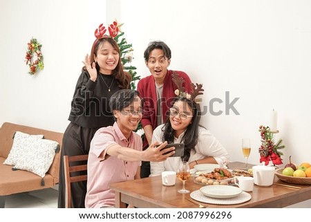 Four asian people taking a picture after celebrating christmas and eating together. They looks very happy. Merry Christmas everyone!                             