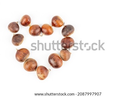 Fresh chestnuts in the form of a heart on a white background. Flat lay background with chestnuts in the form of a heart on white background Autumn and winter concept for love, romance and St.  Royalty-Free Stock Photo #2087997907