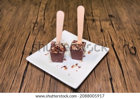Two square-shaped hot chocolate dipping spoons or stirrers on a white plate.