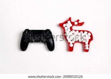 Joystick gaming controller with marshmallows in a plate in the form of a deer on white background. Xmas holiday sale or leisure concept.