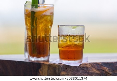 Glasses of iced green tea and peach iced tea with lemon slice on a wooden table. Selective focus.