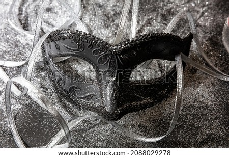 Carnival Venetian mask black and shiny silver streamers festive background, Traditional festival female disguise, Mardi Gras event masquerade
