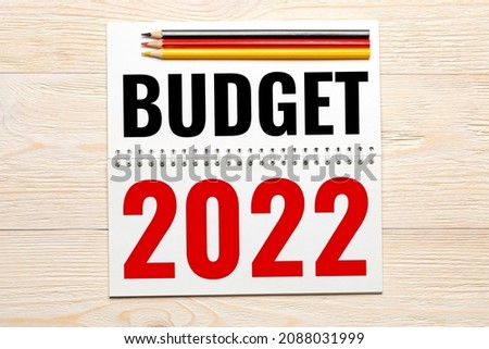 budget 2022 in notepad with black red yellow pencils on wooden table