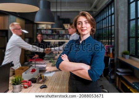 Young caucasian woman entrepreneur is smiling and standing cross hands while her coworker is handshaking with the new business partner for startup design company and agreement