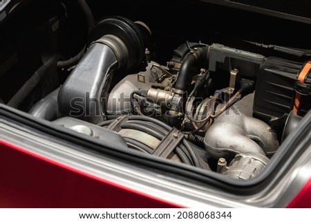 Sports car engine is under open hood, red roadster turbo motor Royalty-Free Stock Photo #2088068344