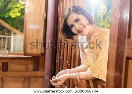 Woman posing in Thai dress, Happy New Year in Thai cultural style, wearing Thai dress, taking pictures with different colors in the background, photographing in a Thai house.