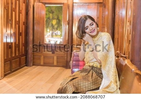 Woman posing in Thai dress, Happy New Year in Thai cultural style, wearing Thai dress, taking pictures with different colors in the background, photographing in a Thai house.