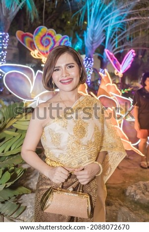 Woman posing in Thai dress, Happy New Year in Thai cultural style, wearing Thai dress, taking pictures with different colors in the background, with beautiful lighting, looks like a butterfly.