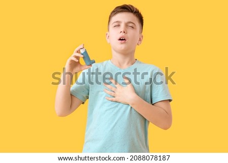 Little boy with inhaler having asthma attack on color background Royalty-Free Stock Photo #2088078187
