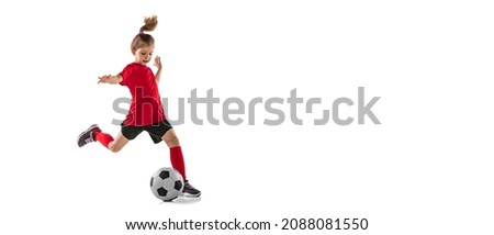 Portrait of sportive child, girl in red uniform playing, training football isolated over white background. Concept of action, sportive lifestyle, team game, health, energy, vitality and ad Royalty-Free Stock Photo #2088081550
