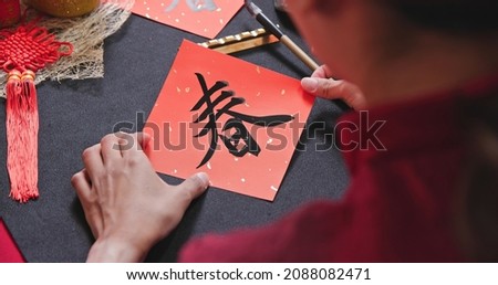 close up of asian woman finish writing Chinese festival couplet to celebrate new year with word meaning spring Royalty-Free Stock Photo #2088082471