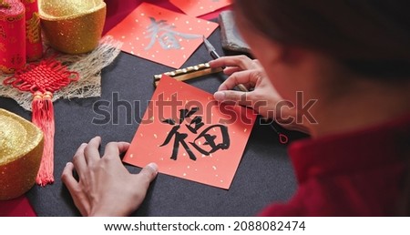 asian woman write spring Chinese festival couplet to celebrate new year with word meaning lucky Royalty-Free Stock Photo #2088082474