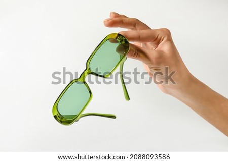 Female hand with stylish sunglasses on light background Royalty-Free Stock Photo #2088093586