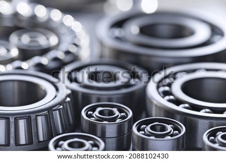 Set of deep groove ball and roller bearings on a gray background with soft focus. Axial chrome plated round bearings for heavy equipment and mechanical engineering close-up. Royalty-Free Stock Photo #2088102430