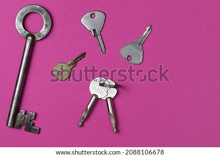 Keys on pink background, flat lay, trendy colorful photo with colored paper.