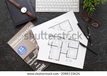 House plans, magazine and computer keyboard on dark background