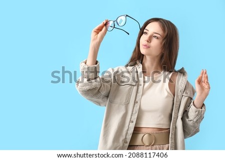Young woman wearing eyeglasses on color background Royalty-Free Stock Photo #2088117406
