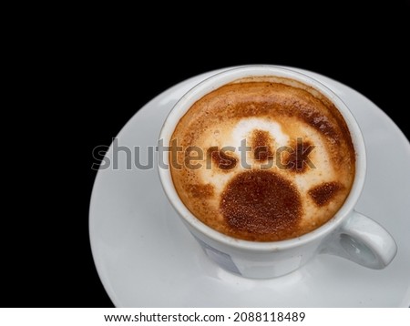 Top view of coffee cup with latte art design on black background