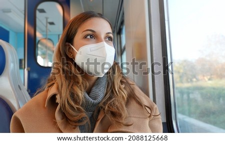 Travel safely on public transport. Panoramic banner of beautiful woman wearing FFP2 KN95 face mask on train looking through the window. Royalty-Free Stock Photo #2088125668