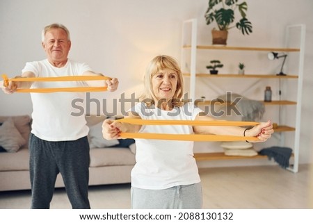 Doing stretching and fitness exercises. Senior man and woman is together at home. Royalty-Free Stock Photo #2088130132
