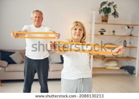 Doing stretching and fitness exercises. Senior man and woman is together at home. Royalty-Free Stock Photo #2088130213